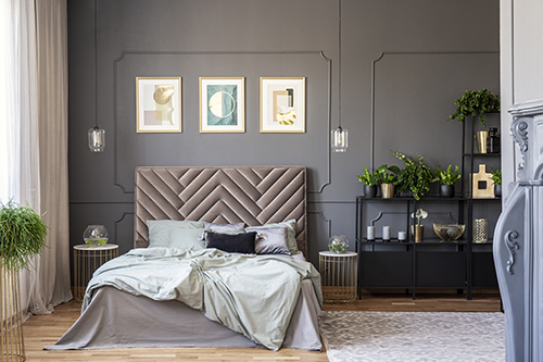 Sweet Dreams: Our 2020 Bedroom Interiors Trend Predictions by Fashion Du Jour LDN. Close-up of a velvet headrest, posters on the wall, pillows and glass lamps in a grey bedroom interior
