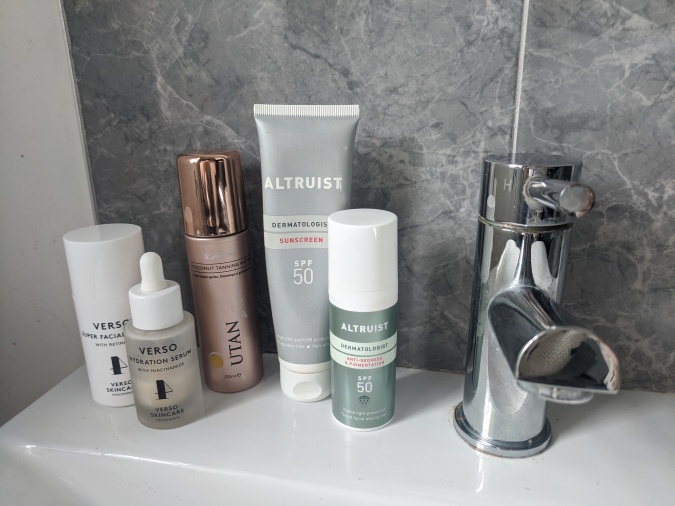 Pandemic Pampering How To Lockdown Your Winning Morning Routine by Fashion Du Jour LDN. Grey marble bathroom tiles with silver tap and white sink,various skincare products by Verso, U-Tan and Altruist Suncare